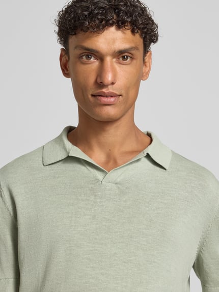 Männermodel trägt Regular Fit Poloshirt aus Baumwoll-Leinen-Mix Modell 'MATTIS' von SELECTED HOMME in Hellgrün, Feinstrickstruktur, unifarben, Nahaufnahme Oberkörper.