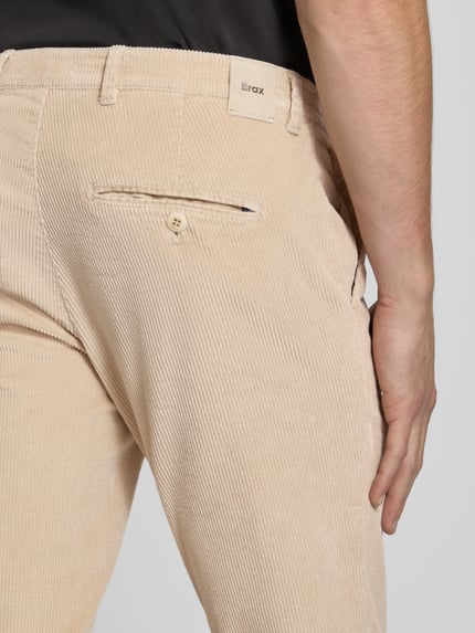 Männermodel trägt Modern Fit Cordhose aus Baumwoll-Mix Modell 'Fabio' von Brax in Beige mit feiner Cordstruktur, Nahaufnahme Rückansicht. Herren Cordhose von Brax.