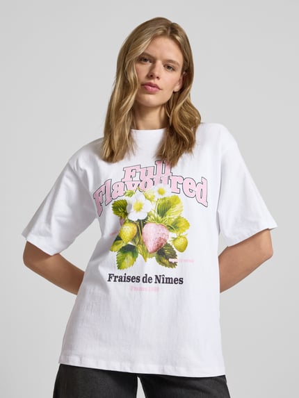 Frauenmodel trägt Loose Fit T-Shirt mit Motiv-Print Modell 'MILLOW' von JJXX aus weißer Baumwolle, Rundhalsausschnitt, Ganzkörperansicht von vorne.