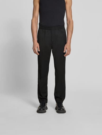 Männermodel trägt Straight Fit Stoffhose mit Woll-Anteil von Filippa K, Elastischer-Material-Mix, Eingrifftaschen, Bundfalten, Ganzkörperansicht von vorne.