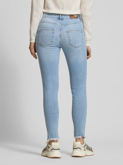Vrouwenmodel draagt Skinny Fit Jeans uit katoenmix model 'BLUSH' van ONLY in denimlook met labelpatch, riemlussen, 5-pocketmodel, knoop- en ritssluiting, materiaal: katoenmix. Volledige lichaamsweergave achteraan.