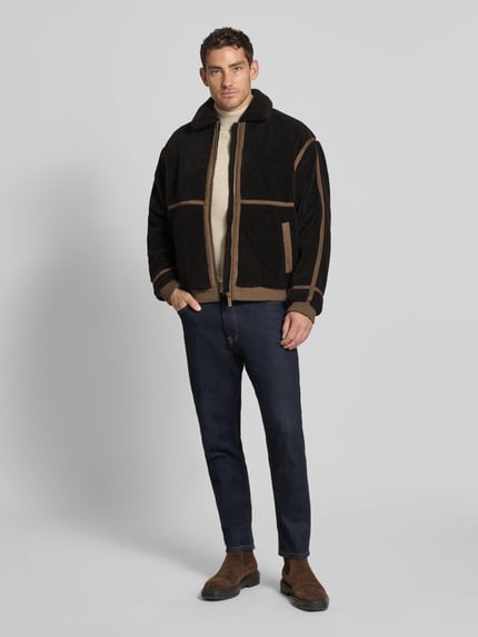 Männermodel trägt Teddy-Jacke mit Reißverschluss von MCNEAL, Regular Fit, schwarz-braun, Umlegekragen, Eingrifftaschen, Ganzkörperansicht von vorne.