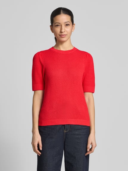 Vrouwenmodel draagt Slim Fit T-shirt in tricotlook model 'Vidalo' van Vila, puur katoen, ronde hals, rode kleur, voorkant volledig zichtbaar, Ganzkörperansicht von vorne.
