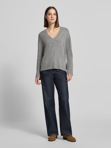 Frauenmodel trägt Pullover aus Wolle mit Logo-Detail von Tommy Hilfiger, Grau Melange, Strukturmuster, Strick, Ganzkörperansicht von vorne.