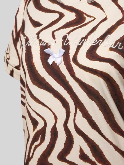 Vrouwenmodel draagt Nachthemd aus reiner Baumwolle Modell 'Wild und Wunderbar' van LOUIS & LOUISA, bruin-wit zebrapatroon, ronde hals, met korte mouwen, statement-stitching en sierstrik, detailopname bovenlichaam.