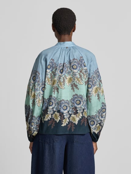 Vrouwenmodel draagt Relaxed Fit Bluse aus reiner Baumwolle van Rich & Royal met opstaande kraag, all-over bloemenprint, met lange mouwen, knoopsluiting, puur katoen. Ruglengte maat 36: 59 cm, mouwlengte maat 36: 66 cm. Ganzkörperansicht Rückansicht.
