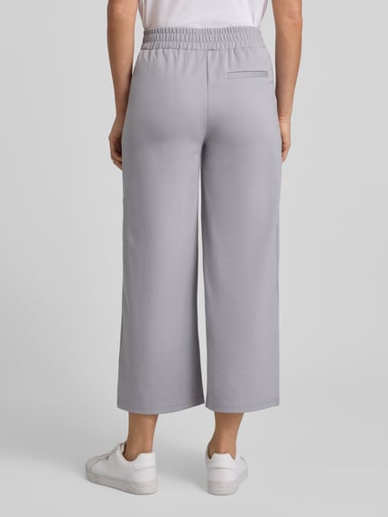 Frauenmodel trägt Wide Fit Stoffhose mit Viskose-Anteil Modell 'Kate' von ICHI in Hellgrau, elastischer Bund, Gesäßtasche, Ganzkörperansicht Rückansicht.