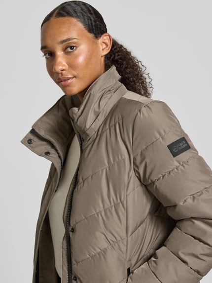 Frauenmodel trägt Regular Fit Jacke in Stepp-Optik von NAUTGÅRD mit Kunstfellbesatz und Eingrifftaschen, Nahaufnahme Oberkörper.