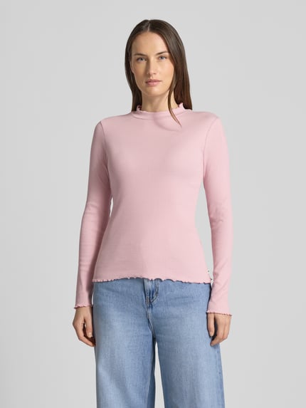 Frauenmodel trägt Slim Fit Langarmshirt aus Baumwoll-Mix von Tom Tailor Denim in Rosa, feine Rippstruktur, Frill-Abschlüsse, hochgeschlossen, unifarben, Label Patch, Ganzkörperansicht von vorne.