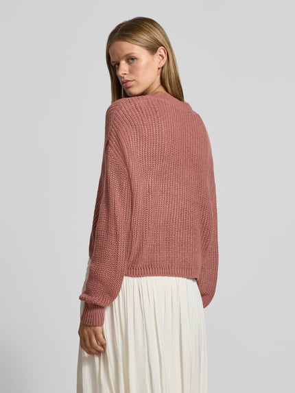 Frauenmodel trägt Boxy Fit Strickjacke mit V-Ausschnitt Modell 'CAROL' von ONLY in Altrosa, grobe Strickstruktur, Damen Strickjacke, Ganzkörperansicht Rückansicht.