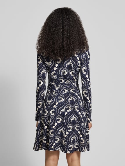 Vrouwenmodel draagt Vrijetijdsjurk van viscosemix Model 'SAVANA' van Weekend Max Mara met all-over motief, getailleerde pasvorm, midilengte, ronde hals, strikceintuur, lange mouw en rechte zoom, jersey materiaalverwerking, achteraanzicht hele lichaam.