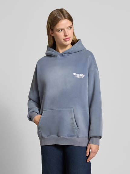 Frauenmodel trägt Oversized hoodie z nadrukiem z logo, efekt znoszenia, mieszanka bawełny, kieszeń kangurka, model 'Wine & Vibe' od ANOTHER COTTON LAB, styl casual, odcień szaroniebieski, gładka faktura, Ganzkörperansicht von vorne.
