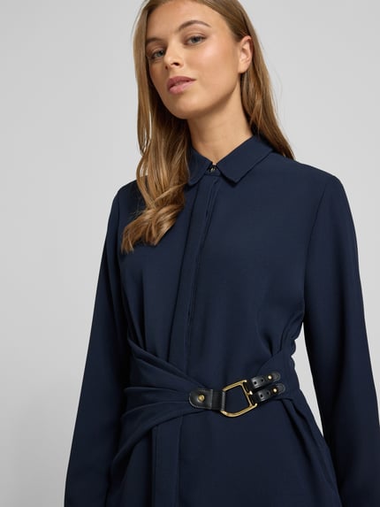 Frauenmodel trägt Bluse in Wickel-Optik Modell 'KRESHAY' von Lauren Ralph Lauren in Dunkelblau, verdeckte Knopfleiste, Schnalle, Nahaufnahme Oberkörper. Kontext: Damen Bluse, Taillierter Schnitt, Hemdblusenkragen, Rückenlänge 67 cm, Ärmellänge 61 cm bei Größe 36.