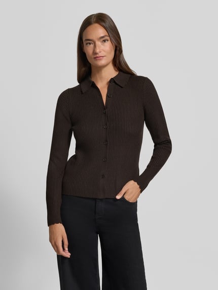 Frauenmodel trägt Cardigan aus Lanawolle mit Polokragen Modell 'ARHANYA' von DRYKORN, Ripp-Optik, Knopfleiste, Slim Fit, Ganzkörperansicht von vorne.