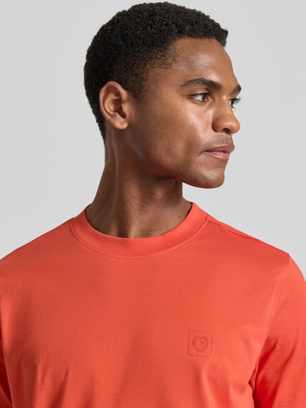 Männermodel trägt T-Shirt mit Rundhalsausschnitt und Logo-Print von Lerros in Orange, Baumwoll-Mix, Regular-Fit, Nahaufnahme Oberkörper. Rückenlänge bei Größe M: 71 cm.
