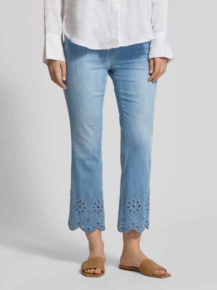 Vrouwenmodel draagt lichtblauwe dames broek met ajourwerk, steekzakken, verkorte pasvorm, Hose mit Lochstickerei Modell 'KICK' van MAC, ganzlichaamsvooraanzicht. Context: dames broek van MAC, verkorte pasvorm, ajourwerk, model 'KICK', steekzakken, bandwijdte bij maat 36: 41 cm, binnenbeenlengte bij maat 36: 68 cm.