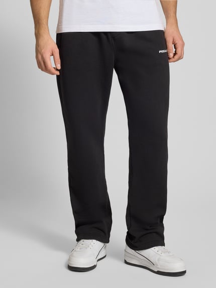Männermodel trägt schwarze Sweathose mit elastischem Bund von Pegador, lockerer Schnitt, Label-Stitching, Nahaufnahme Unterkörper
