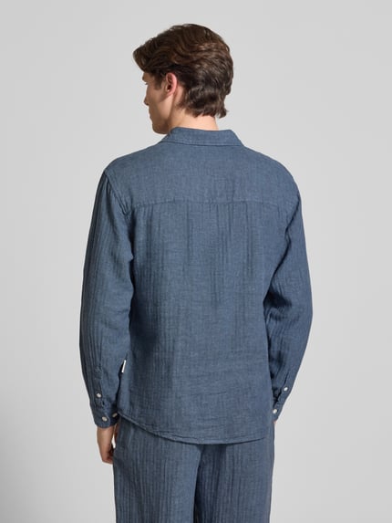 Männermodel trägt Slim Fit Freizeithemd aus Leinen-Baumwoll-Mix Modell 'NELSON' von Redefined Rebel, dunkelblau, strukturierte Oberfläche, Rückenlänge 50 cm, Schulterbreite 49 cm, Ärmellänge 72 cm, mit Kentkragen, Brusttasche und Label-Detail, Ganzkörperansicht Rückansicht.