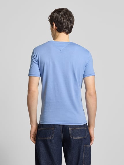 Männermodel trägt Regular Fit T-Shirt aus Baumwoll-Mix von Tommy Jeans in Optik: Unifarben, Jersey-Textur, Ganzkörperansicht Rückansicht.