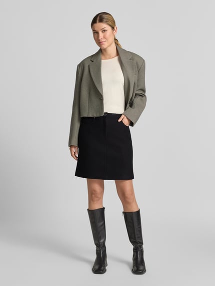 Vrouwenmodel draagt Gerader Mini-Rock aus reiner Schurwolle van Marc Cain in zwart, rechte lijnen, gladde textuur, volledig frontaal.