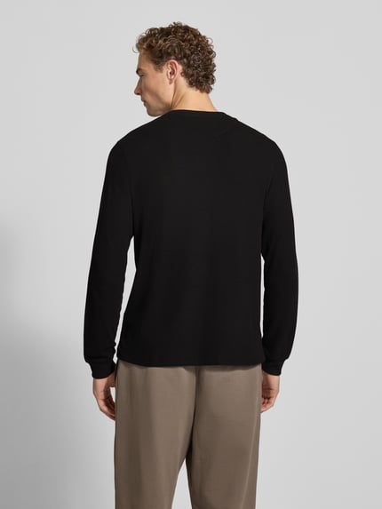 Männermodel trägt Regular Fit Langarmshirt aus reiner Baumwolle von Lacoste in Schwarz, lockere Form, leichte Textur, Ganzkörperansicht Rückansicht.