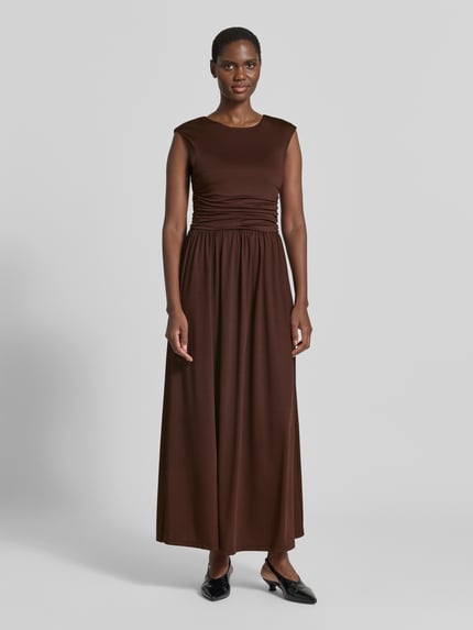 Frauenmodel trägt Maxikleid mit Kappärmeln Modell 'WINJA' von YAS in Braun, taillierter Schnitt, Stoff mit Stretch, Ganzkörperansicht von vorne.