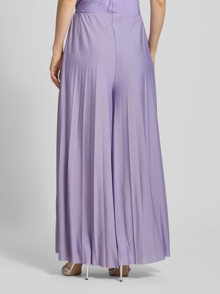 Frauenmodel trägt Wide Fit Stoffhose in Falten-Optik Modell 'Samantha' von GUIDO MARIA KRETSCHMER WOMAN, lila, fließender Stoff, Ganzkörperansicht Rückansicht, Bundweite 36 cm, Innenbeinlänge 75 cm.