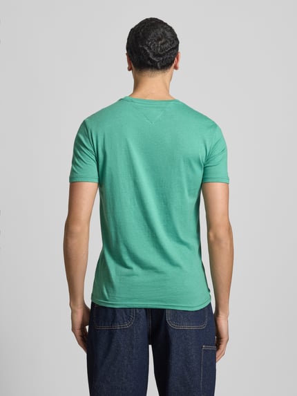 Männermodel trägt Slim Fit T-Shirt aus Baumwoll-Mix Modell 'JASPE HERITAGE' von Tommy Jeans in Melange-Optik, Ganzkörperansicht Rückansicht.