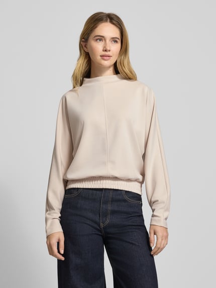 Frauenmodel trägt Sweatshirt mit geripptem Stehkragen Modell 'Gulitta' von Opus im Modal-Mix mit Stretch-Anteil, lockerer Schnitt, elastischer Bund, helle Farbe, glatte Textur, Ganzkörperansicht von vorne.