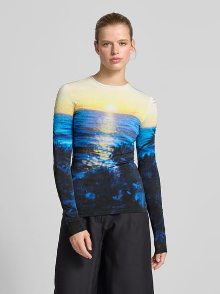 Frauenmodel trägt Slim Fit Longsleeve aus Viskose-Mix von Rabanne mit Allover-Foto-Print in Gelb und Blau, Rundhalsausschnitt, Ganzkörperansicht von vorne.
