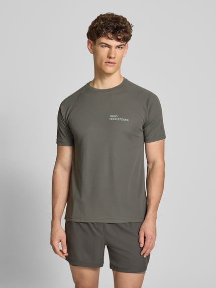 Mężczyzna nosi T-Shirt mit Label-Print Modell 'SORONA' von HALO, kolor szary, krój regular fit, okrągły dekolt, długość tyłu w rozmiarze M: 69 cm, widok całej sylwetki z przodu.