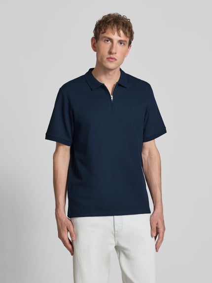 Männermodel trägt Regular Fit Poloshirt mit Reißverschluss Modell 'AUSTIN' von Jack & Jones, Material-Mix mit Baumwoll-Anteil, Strukturmuster, dunkelblau, Rückenlänge 69 cm bei Größe M, Ganzkörperansicht von vorne.
