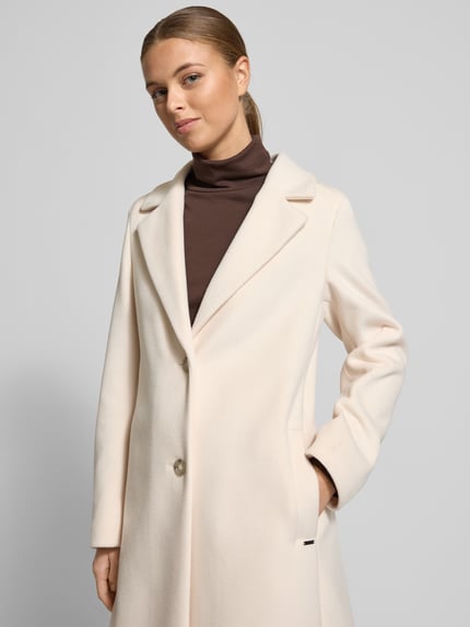 Frauenmodel trägt Mantel mit Kapuze Modell 'MIRA' von Cinque in Creme, Regular Fit, Reverskragen, Eingrifftaschen, Nahaufnahme Oberkörper.