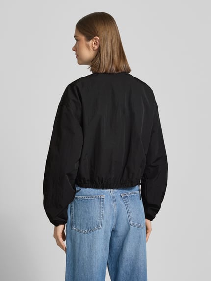 Frauenmodel trägt Relaxed Fit Blouson mit Taillenbändern von Tommy Jeans, Optik: Unifarben, Passform: Relaxed-Fit, Stehkragen, Verschluss: Reißverschluss, Logo-Stitching, Langarm, elastischer Ärmelabschluss, seitliche Eingrifftaschen mit Druckknopf, Ganzkörperansicht Rückansicht.