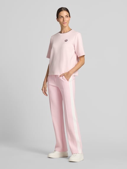 Frauenmodel trägt Straight Fit Hose mit Tunnelzug von Marc Cain, floraler Print, elastischer Bund, Rosa und Weißtöne, Ganzkörperansicht von vorne.