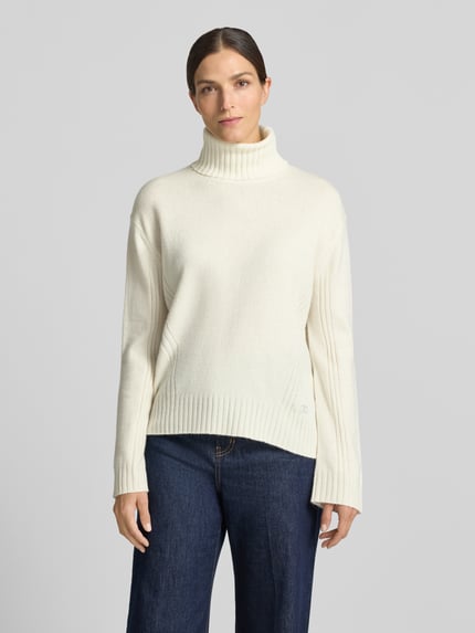 Frauenmodel trägt Relaxed Fit Rollkragenpullover aus reiner Wolle von Liu Jo White, weiße Farbe, Strasssteine, gerippte Abschlüsse, Ganzkörperansicht von vorne.