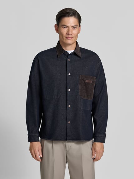 Männermodel trägt dunkelblaues Overshirt mit Kentkragen in Cord-Optik und Label-Patch von Armani Exchange, Regular fit, Knopfleiste, Brusttasche, Sportmanchetten, Rückenlänge 70 cm, Ganzkörperansicht von vorne.