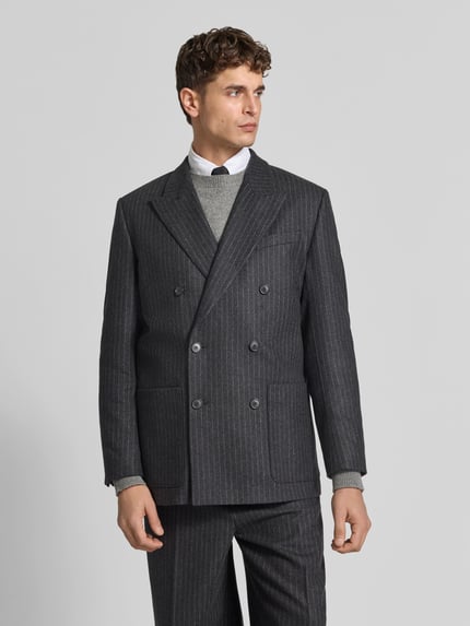 Männermodel trägt Regular Fit Sakko aus Woll-Mix von Filippa K in Dunkelgrau mit feinen Nadelstreifen, Doppelreiher, Ganzkörperansicht von vorne.
