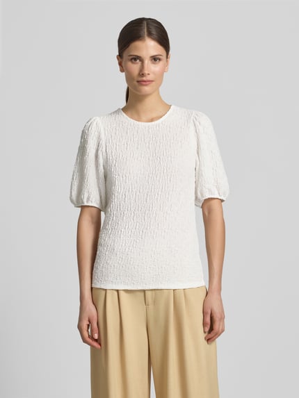 Vrouwenmodel draagt Blusenshirt met structuurpatroon model 'FALL' van Vila, materiaalmix met stretch, regular fit, witte kleur, ronde hals, dames, vooraanzicht hele lichaam.