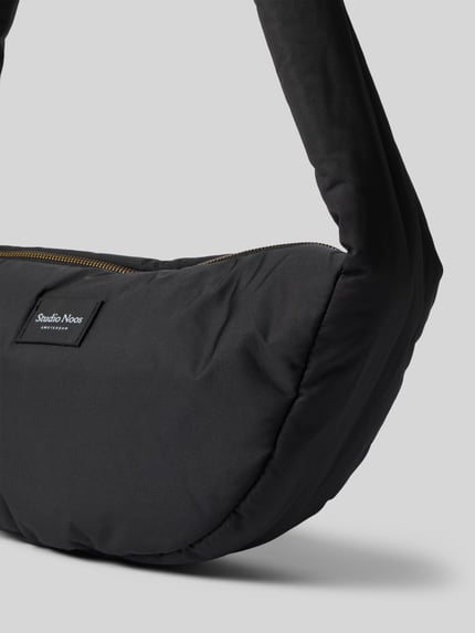 Produktfoto, czarna torba na ramię Shoulder Bag mit Logo-Detail Model 'Puffy' od Studio Noos, detal z logo, Główna przegroda z zamkiem błyskawicznym, szerokość w rozmiarze 1: 38 cm, długość w rozmiarze 1: 20 cm, głębokość w rozmiarze 1: 9 cm, długość paska na ramię w rozmiarze 1: 86 cm, matowa tekstura, zaokrąglony kształt