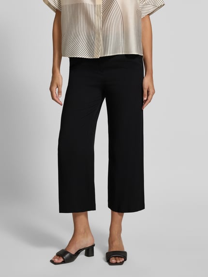 Frauenmodel trägt Culotte aus Viskose mit Gürtel von Christian Berg Woman, schwarze Wide Leg Fit Hose, Nahaufnahme Oberkörper und Beine.