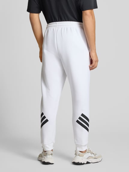 Männermodel trägt Sweatpants mit Logo und elastischem Bund von adidas Sportswear, weiß, Material-Mix mit Baumwoll-Anteil, Regular-Fit, Ganzkörperansicht Rückansicht.
