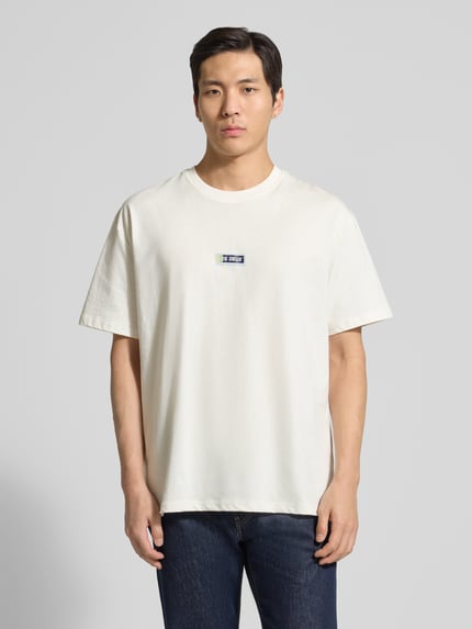 Mannelijk model draagt t-shirt met logoprint model 'Chase' van Les Deux, puur katoen, recht model, ronde hals, labeldetail, ruglengte maat M 72 cm, frontale volledige lichaamsopname.
