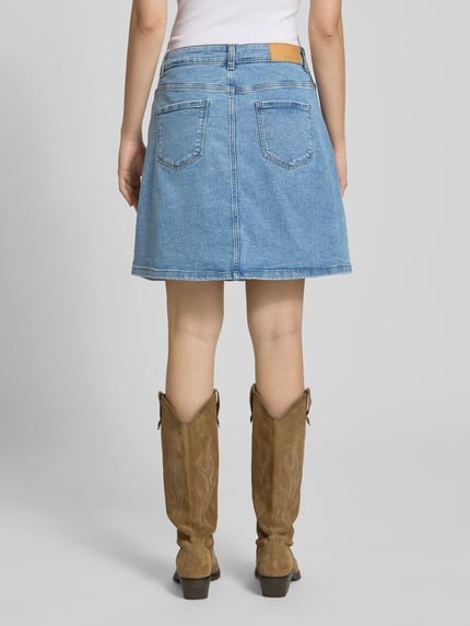 Frauenmodel trägt Jeansrock mit Knopfleiste Modell 'RONNIE' von Noisy May, hellblauer A-Linien-Minirock aus Baumwoll-Mix, Rückansicht Ganzkörperansicht.