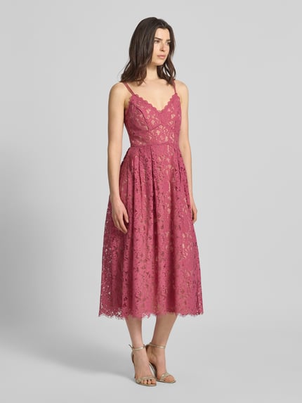 Frauenmodel trägt Knielanges Cocktailkleid mit Spitze und Spaghettiträgern von Jake*s Cocktail, Baumwoll-Mix, Taillierter Schnitt, Knielänge, Spitze, doppelte Spaghettiträger, V-Ausschnitt, rückseitiger Haken- und Reißverschluss, blickdichtes Unterkleid, Farbe Pink, florale Spitzen-Textur, Ganzkörperansicht von vorne.