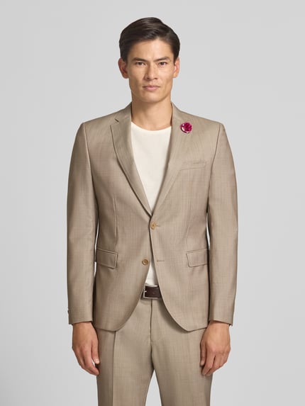 Męski model nosi Slim Fit 2-Knopf-Sakko aus Schurwoll-Elasthan-Mix von CG – CLUB of GENTS beżowy, kołnierz z połami, Kieszenie z patką, Ganzkörperansicht von vorne, marynarka na 2 guziki, długość tyłu w rozmiarze 50: 75 cm, szerokość w rozmiarze 50: 42 cm, długość rękawów w rozmiarze 50: 66 cm, Model 'Patrick'.