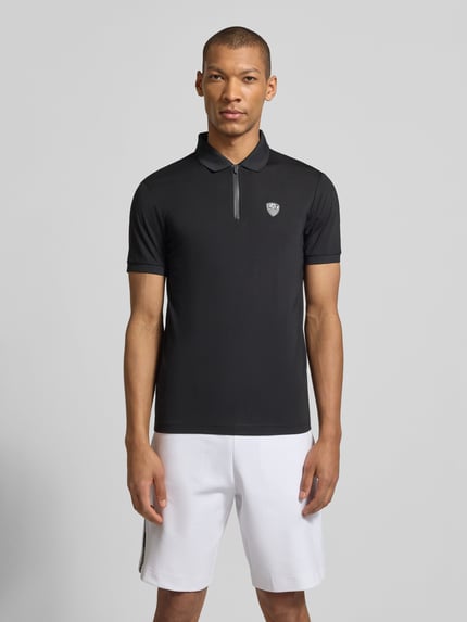 Männermodel trägt Slim Fit Poloshirt aus Viskose-Mix von EA7 Emporio Armani, schwarz, Logo-Detail, elastische Ärmel, Ganzkörperansicht von vorne.