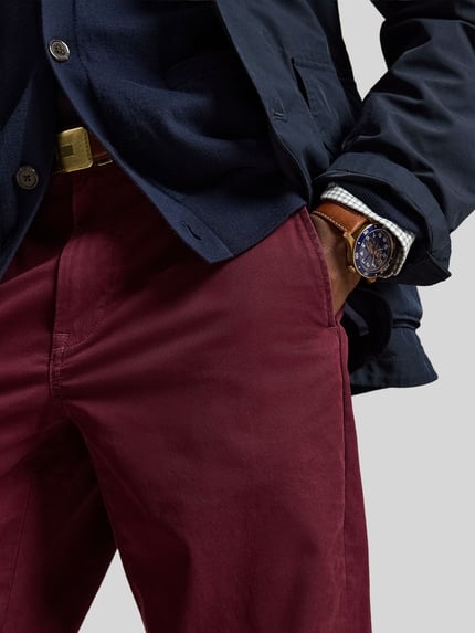 Männermodel trägt Gerade Hose aus Baumwoll-Mix von Polo Ralph Lauren in Dunkelrot, glatte Textur, Nahaufnahme Hüfte und Oberschenkel.