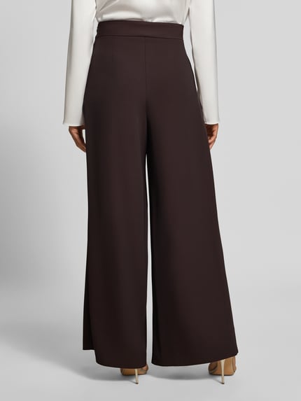 Vrouwenmodel draagt Wide Leg Stoffhose met Reißverschlusstaschen van Rinascimento, Materiaalmix met stretch, bruine kleur, wide fit, elastische band, zij-ritszakken, bandwijdte maat S 37 cm, binnenbeenlengte maat S 82 cm, full body achteraanzicht