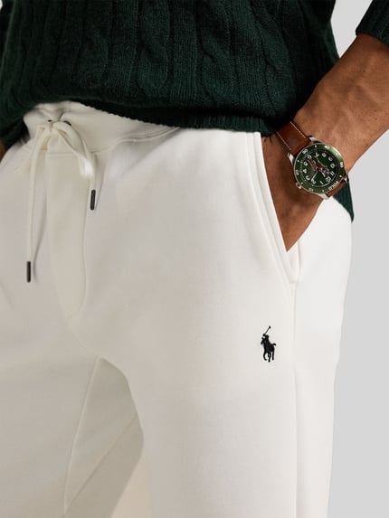 Mannenmodel draagt 'Tapered Sweatshorts aus Baumwoll-Mix' van Polo Ralph Lauren in effen wit met elastische tailleband, logo-stitching en steekzakken, sweatmateriaalmix. Detailopname heup en taille.